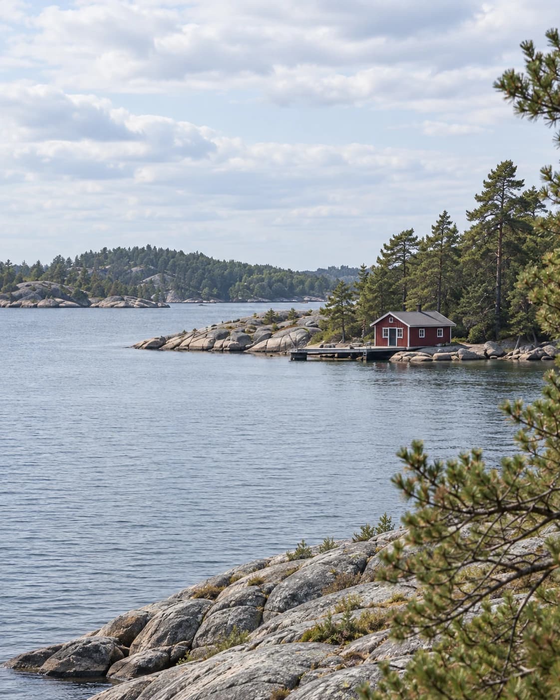 Red wooden house beside water and a granite shoreline